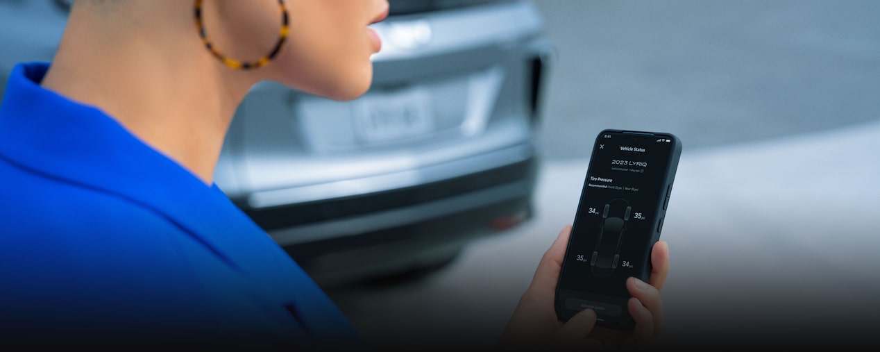 A Woman Wearing a Blue Blazer Uses the MyCadillac Mobile App