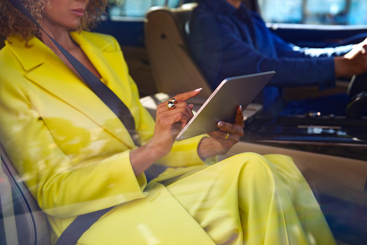 A Fashionably Dressed Woman in the Passenger Seat of a Cadillac on an iPad