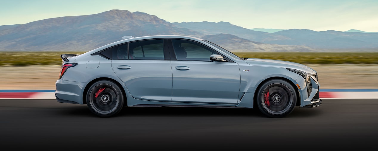 Side View of a Light Blue Cadillac CT5-V Driving Down the Road with Mountains Visible in the Distance
