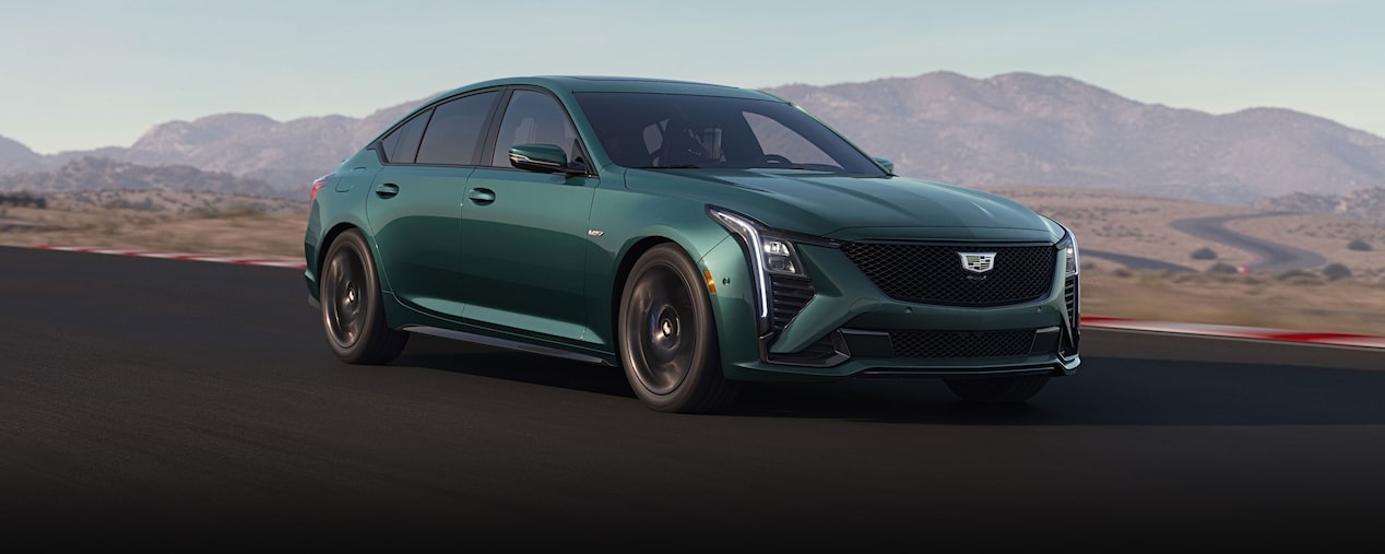 Three-quarters View of a Green Cadillac CT5-V Driving Down the Road Surrounded by Desert