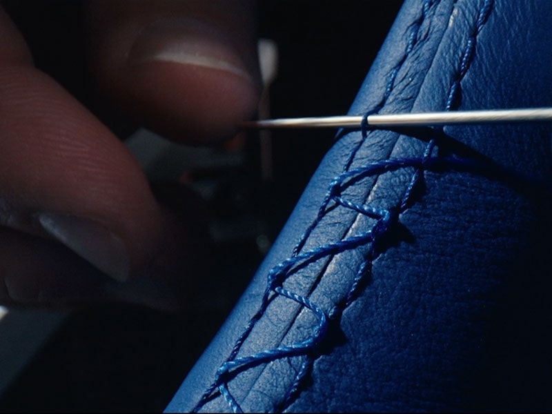 Three-quarter Rear View of a Blue Cadillac CELESTIQ Driving Under a Mountain Sunset