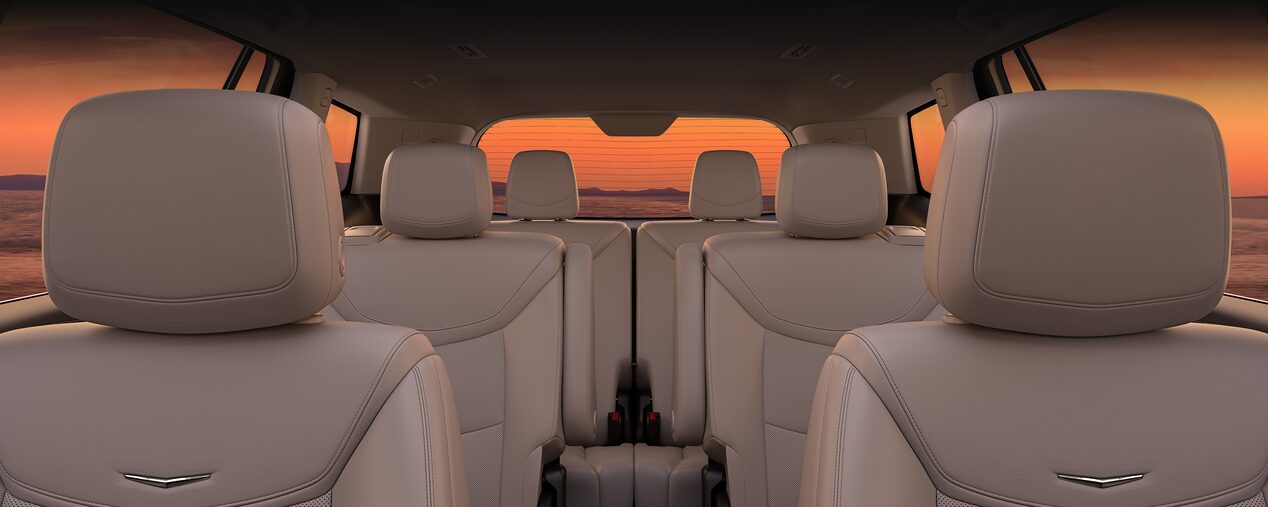 Three Rows of Tan Leather Seats Inside the New Cadillac XT6 Parked Under the Sunset