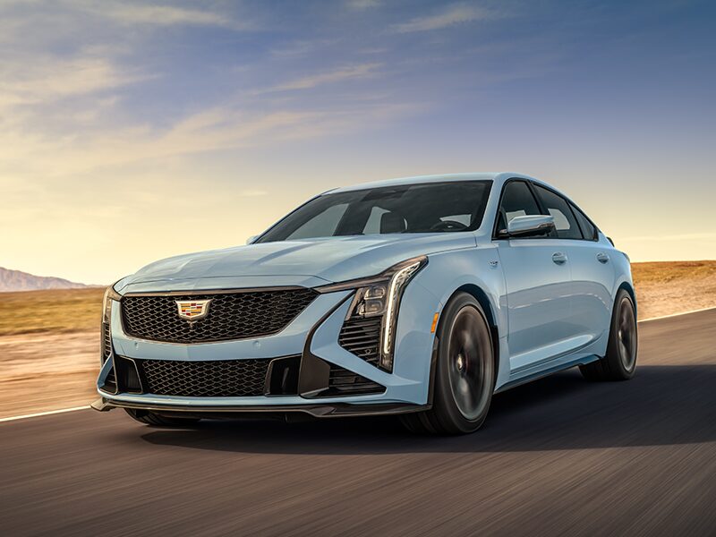 Low Three-Quarters View of a Light Blue Cadillac CT5-V Driving Down the Road Surrounded by Desert