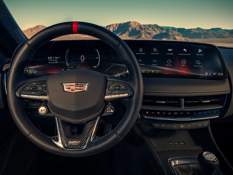 Driver's Seat View of a Cadillac CT5-V Steering Wheel and Dashboard in Front of Mountains