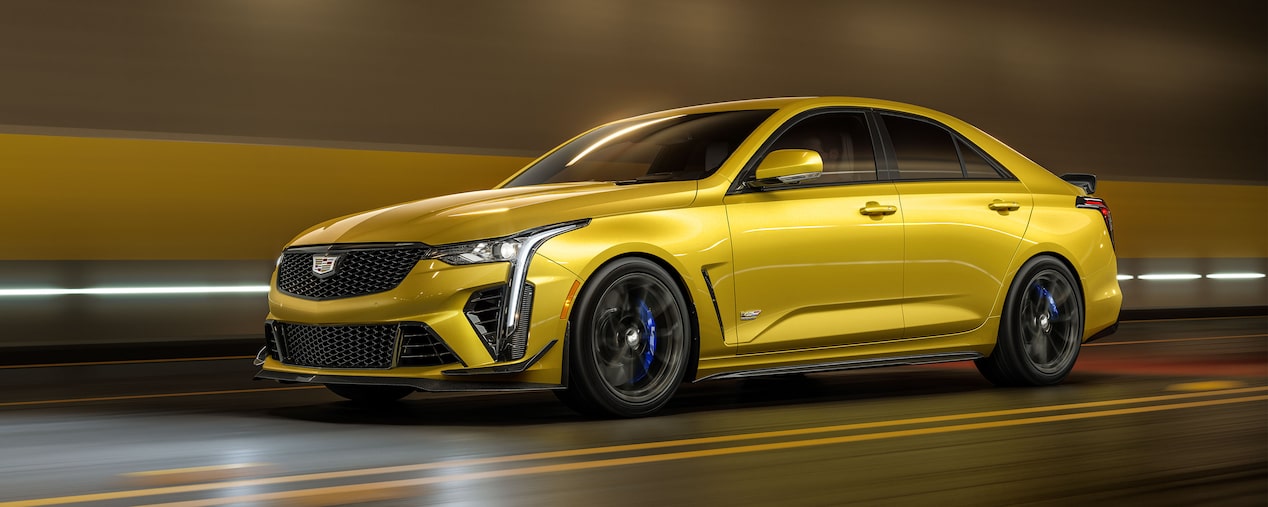 A Yellow Cadillac V-Series Vehicle Driving Through a Tunnel with it's Headlights on.
