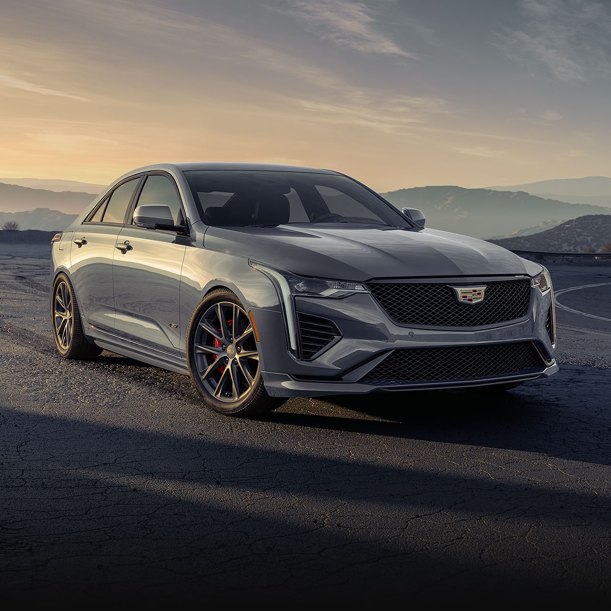 A Cadillac CT4-V Driving Down a Road with Hills in the Background.